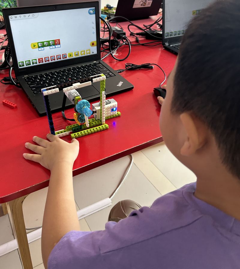 孩子一边编程一边调试机器人