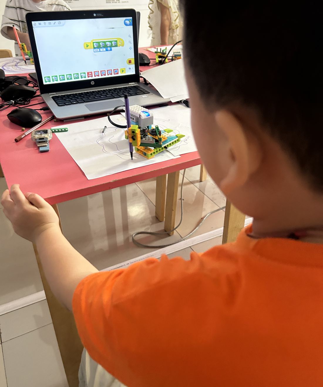 孩子在课堂上用电脑编程，控制自己搭的画图机器人
